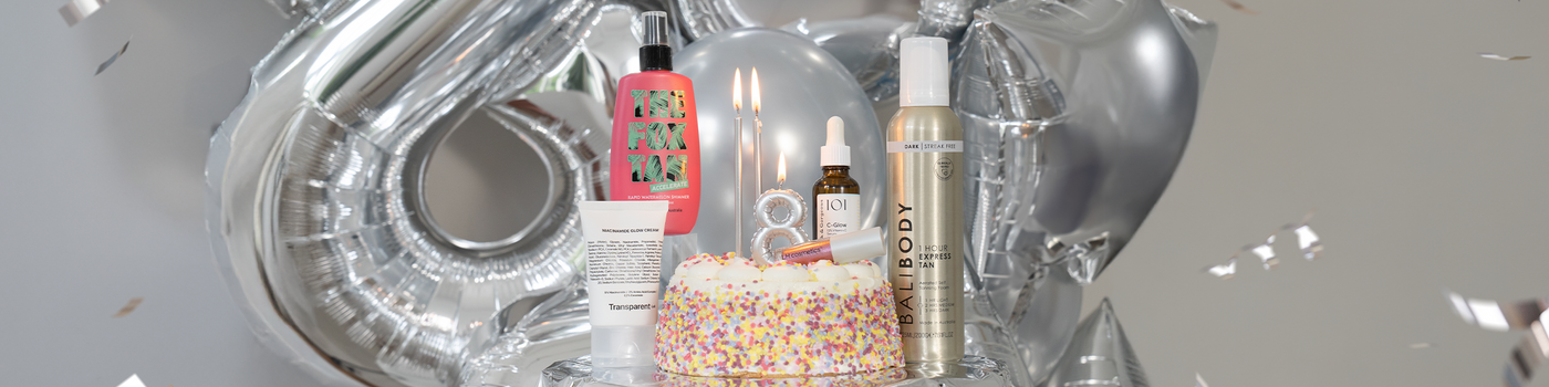 Eine Geburstagstorte mit silberner Kerze in Form einer "8", umringt von Beauty Produkten; dahinter silberne Zahlenluftballons.