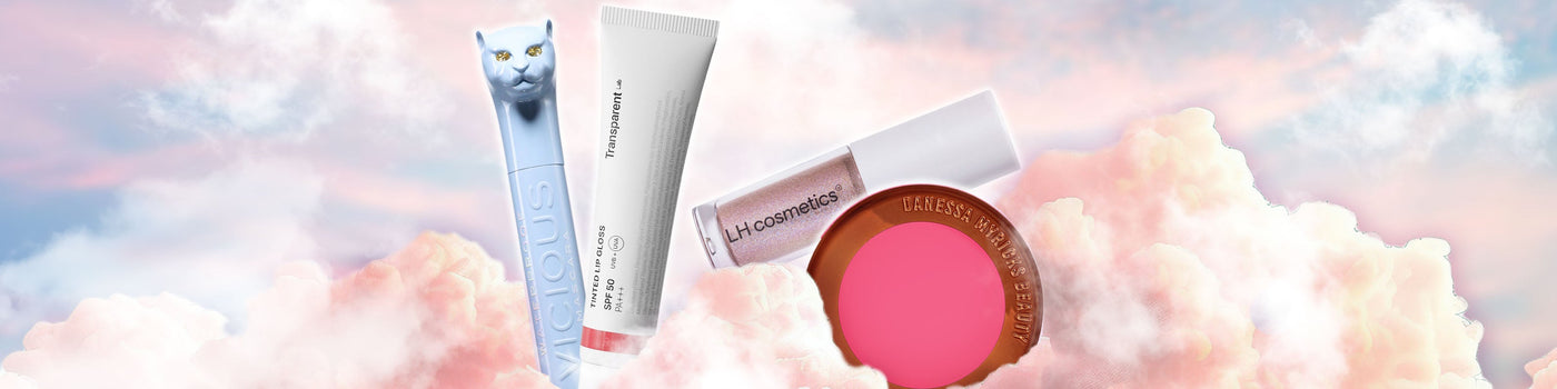 Vier Schönheitsprodukte, darunter Mascaras und Rouge, schweben auf zartrosa Wolken vor einem pastellfarbenen Himmelshintergrund.