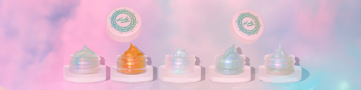 Fünf kleine Tiegel mit schimmernden Gele-Texturen in verschiedenen Farben vor pastellfarbenem Wolkenhintergrund.