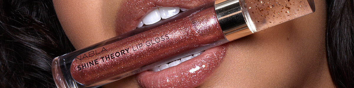 Nahaufnahme glänzender Lippen mit einem schimmernden NABLA Shine Theory Lip Gloss in einem rötlich-braunen Farbton.