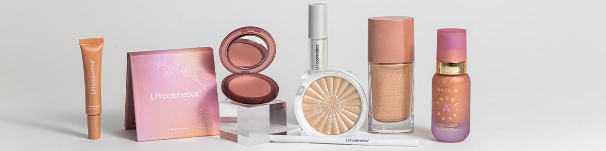 Auf einer weißen Oberfläche werden verschiedene Make-up-Produkte von LH cosmetics präsentiert, darunter Rouge, Highlighter, Foundation und Lipgloss.
