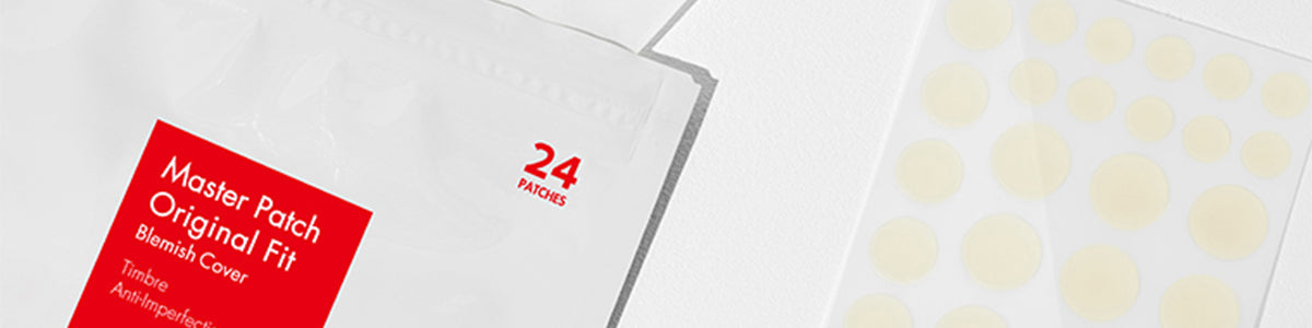 Nahaufnahme einer Packung mit 24 Pflastern gegen Pickel neben einem Blatt mit runden Pickelpflastern.