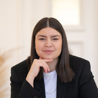 Porträt von Zuzanna mit dunkelbraunen Haaren, braunen Augen und schwarzem Blazer vor hellem Hintergrund.
