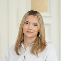 Porträt von Celina mit blonden Haaren, silbernen Ohrringen und weißem Oberteil vor hellem Hintergrund.