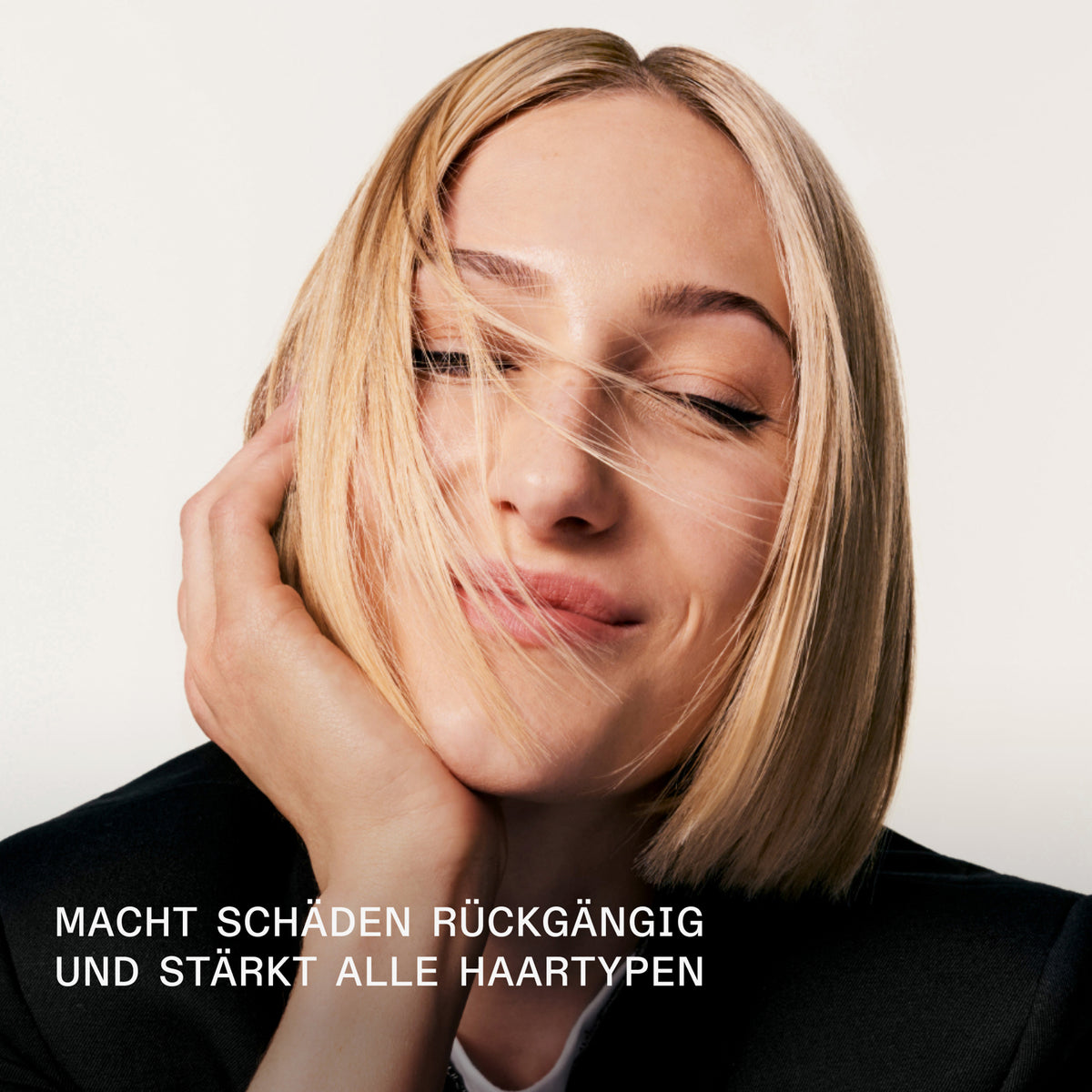 Eine Frau mit blondem Bob lächelt mit geschlossenen Augen; Darunter Text: Macht Schäden rückgängig und stärkt alle Haartypen.