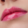Nahaufnahme der Lippen einer Person mit heller Haut mit dem Glossin‘ Glow Tinted Lip Oil 020 in glänzendem Pink.