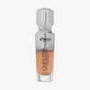 Eine halb transparente halb silberne Flasche Chroma Cover Foundation Luminous in der Farbe C8 vor weißem Hintergrund.