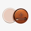 Runder geöffneter Behälter Yummy Skin Blurring Balm Shade 0.5 mit bronzefarbenem Deckel und kleinem Applikator.