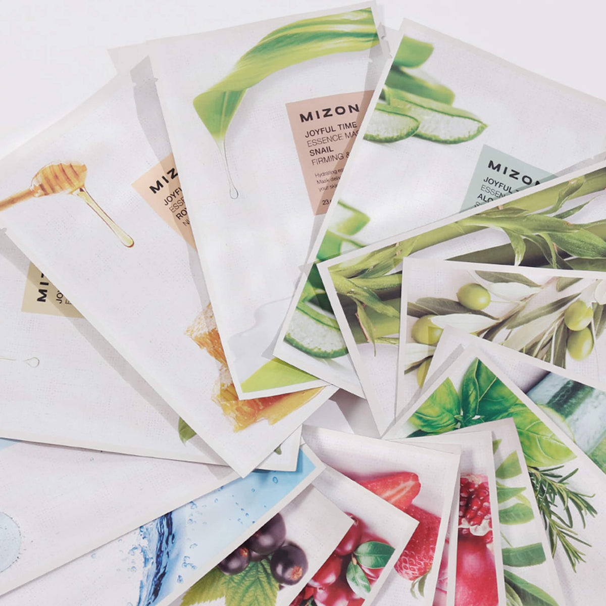 Mehrere bunte Sachets der Mizon Joyful Time Essence Mask, teils überlappend. Zu sehen sind Motive wie Aloe Vera, Honig, Olive und Erdbeere.