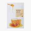 Mizon Joyful Time Essence Mask Royal Jelly mit Honigwabe und tropfendem Honiglöffel auf weißem Sachet, Textfeld in hellem Beige.
