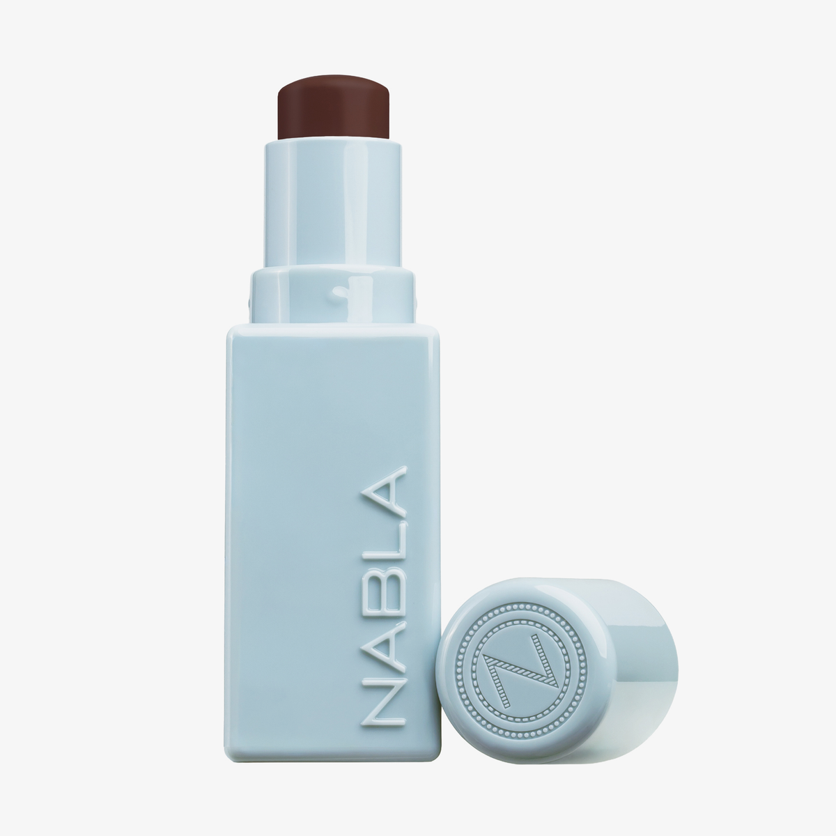 Ein hellblauer NABLA Cosmetics Contour Stick mit abgenommener Kappe, die ein dunkelbraunes Produkt enthüllt.