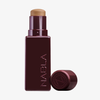 Ein NABLA Cosmetics Art Of Skin Foundation Stick in Burgunderrot, der mit abgenommener Kappe präsentiert wird, um das cremige Produkt im Inneren zu enthüllen.