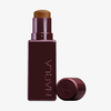 Eine kastanienbraune Tube des NABLA Cosmetics Art Of Skin Foundation Stick mit abgenommener Kappe, die den Blick auf das enthaltene Produkt freigibt.