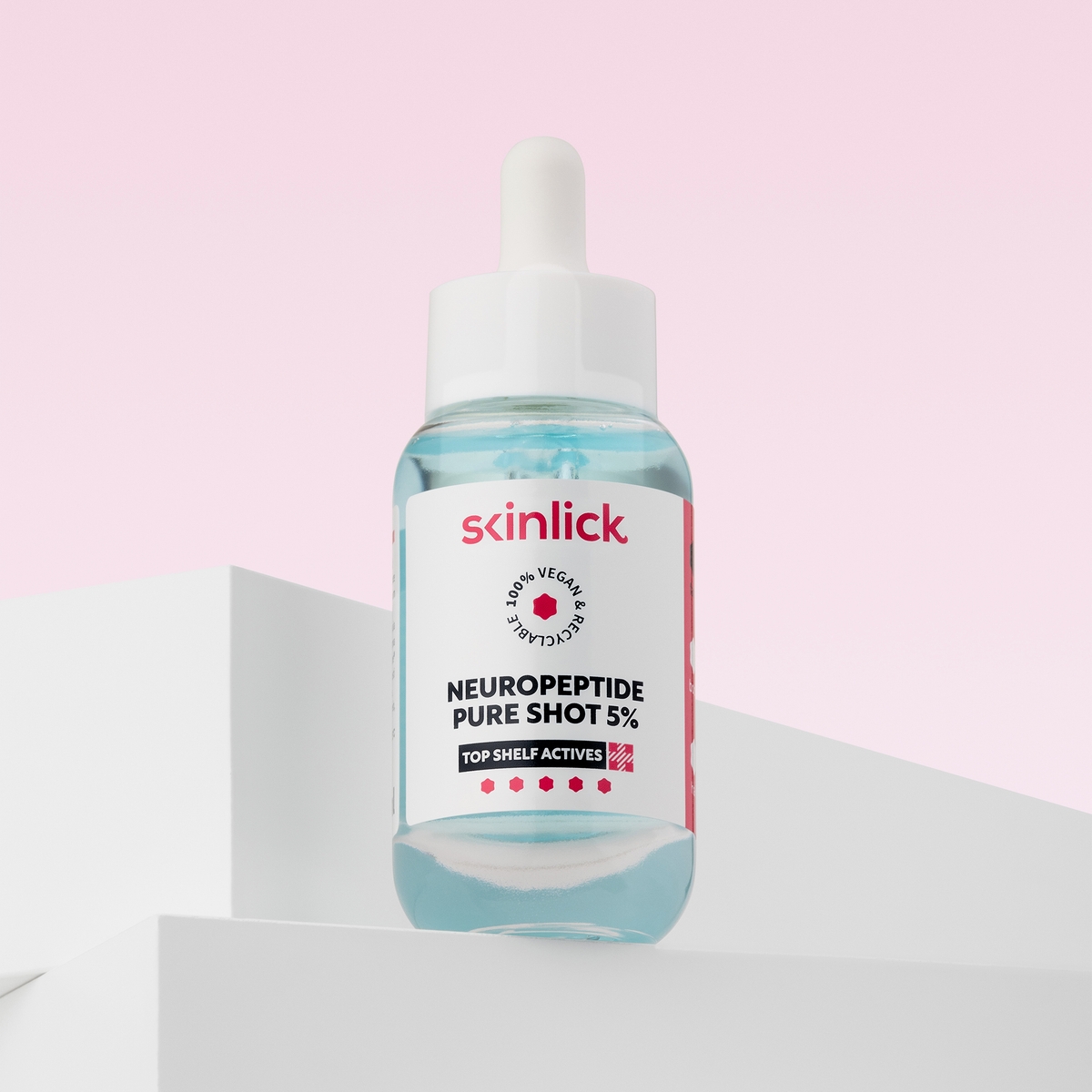 Eine blaue Serumflasche mit Skinlick Neuropeptide Pure Shot 5% steht auf einer weißen Fläche vor einem rosa Hintergrund.