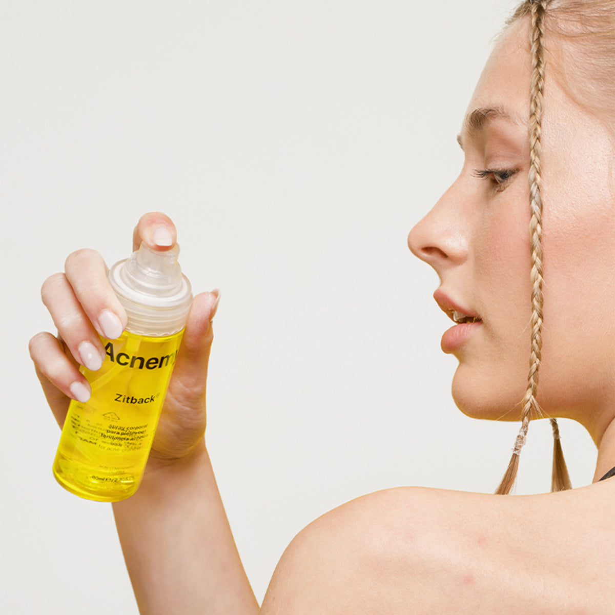 Eine Person hält eine Sprühflasche Zitback über ihre linke Schulter und sprüht sie an