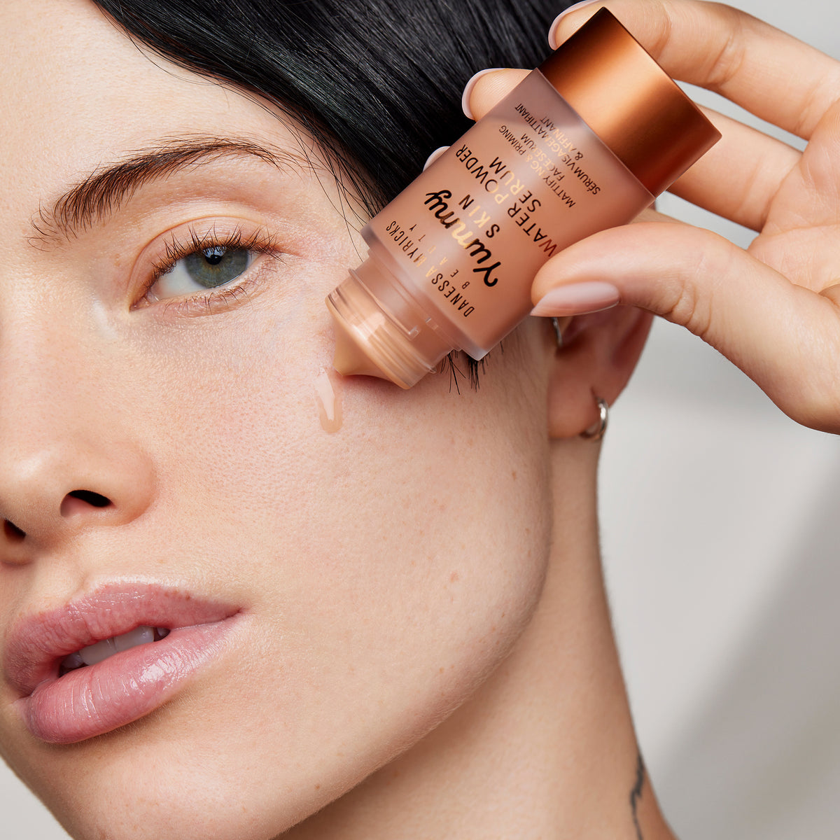 Eine Person trägt einen Tropfen Yummy Skin Water Powder Serum auf ihre Wange auf.