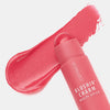 Blushin' Charm Multi Stick 010 mit runder Kuppe auf einem cremigen rosa-rotem Swatch auf weißer Oberfläche.