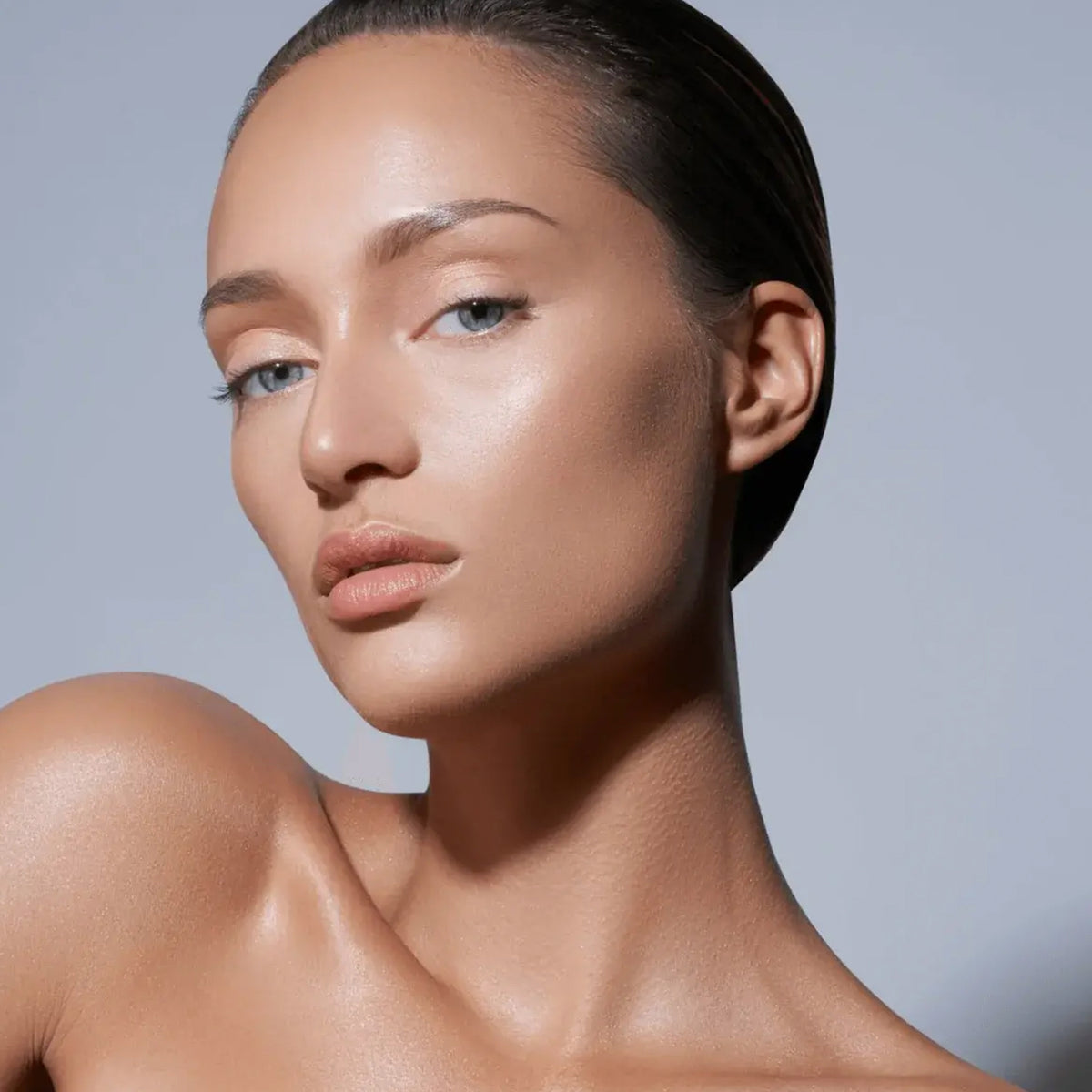 Frau mit glatter, strahlender Haut und zurückgekämmtem Haar präsentiert die Wirkung des Evolution Powder #1 vor schlichtem Hintergrund.
