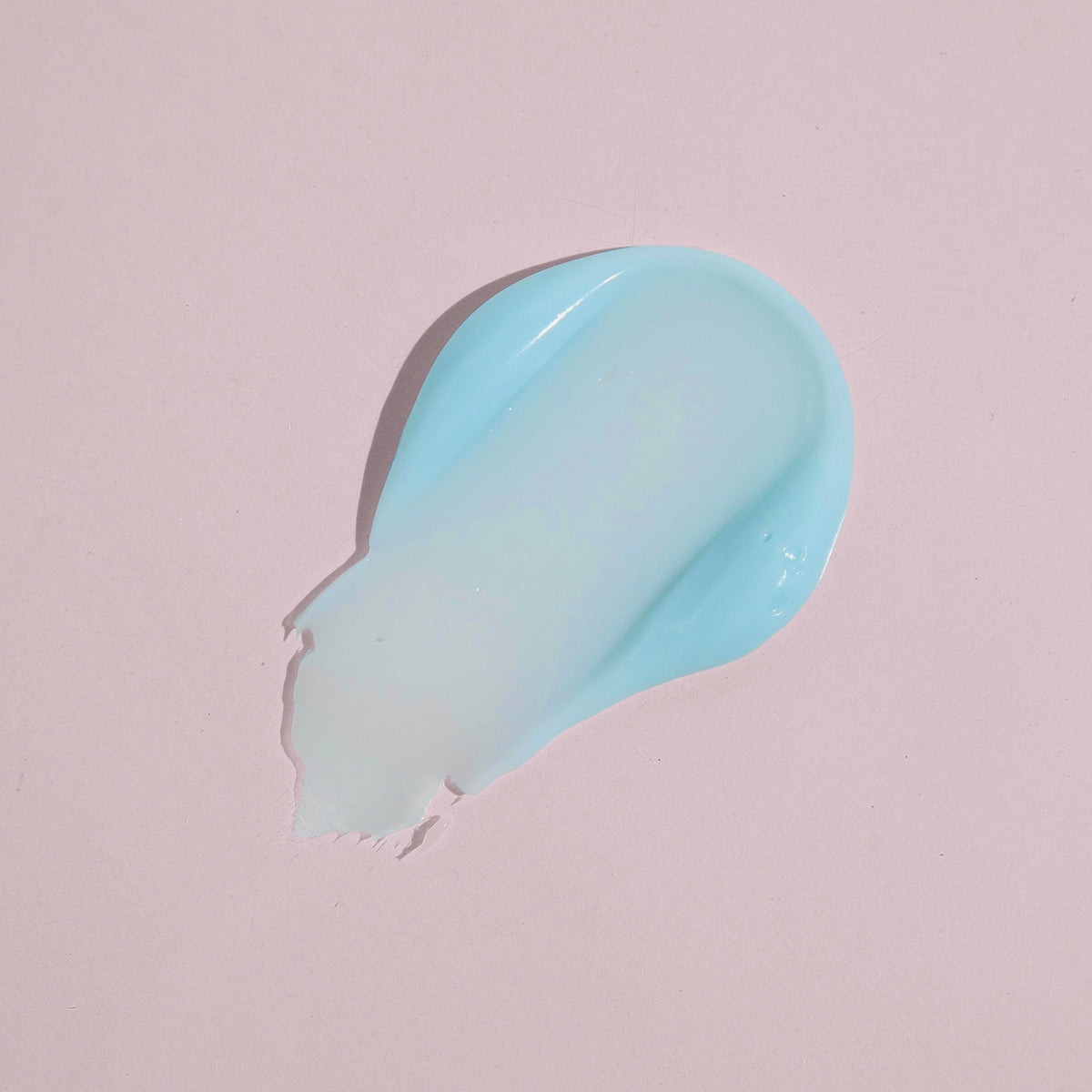 Ein Klecks Cooling Blur Mattifying Primer in hellblauer Gel- oder Cremeform auf einem blassrosa Hintergrund.