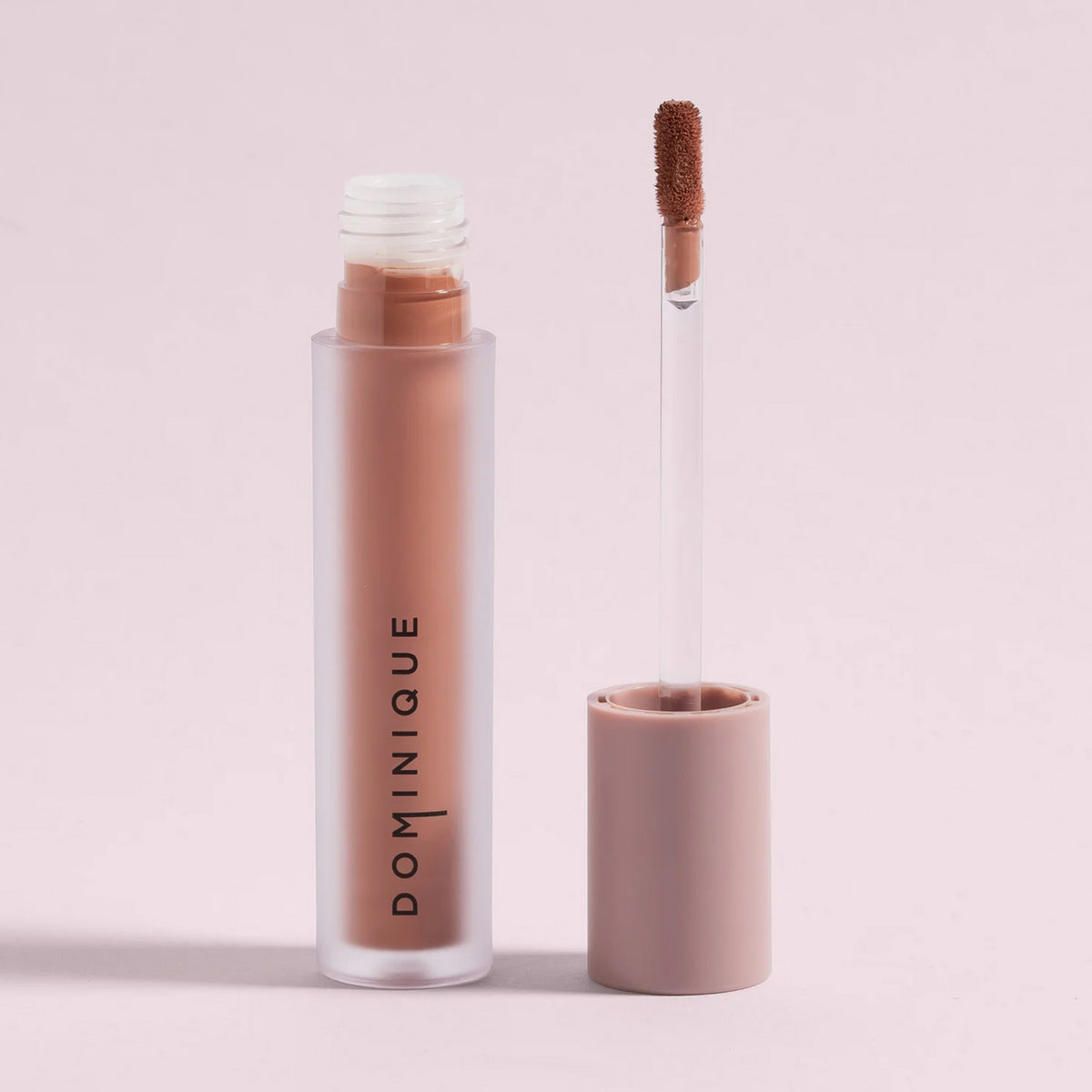 Eine Tube Cream Matte Liquid Lipstick mit dem daneben liegenden Applikator auf einem hellrosa Hintergrund.