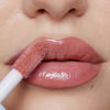 Nahaufnahme voller Lippen, auf die Plumpy Lip Gloss Rose Nude in glänzendem Rosé aufgetragen wird.
