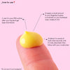Eine Fingerspitze mit einem gelben Cremetropfen A-Game 5; daneben Gebrauchsanweisungen auf rosa Hintergrund.