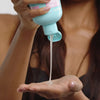 Eine Frau gießt Shampoo aus einer blauen Hairburst-Falsche in ihre Hand.