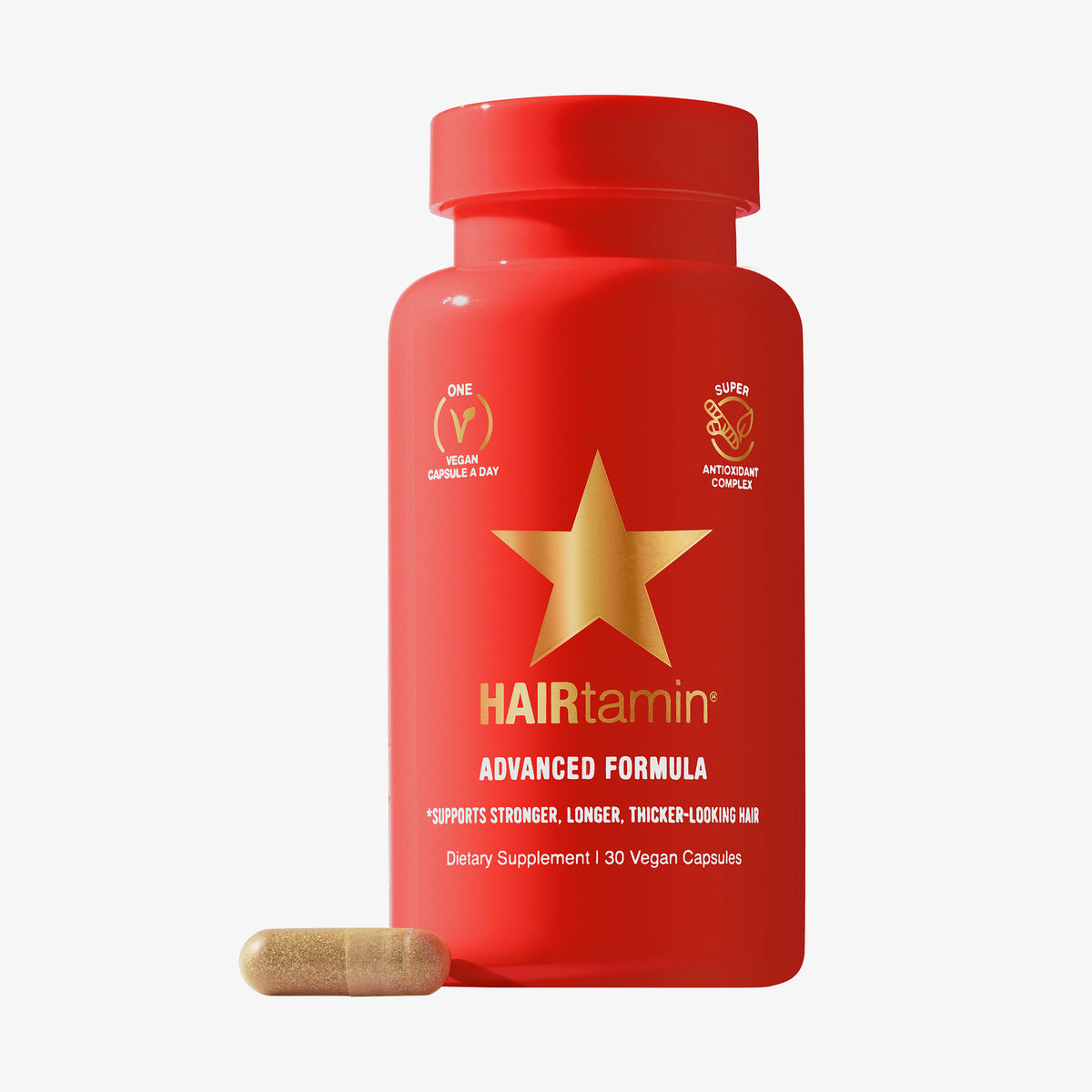 Rote Flasche HAIRtamin Advanced Formula 1 Month mit einem goldenen Stern neben einer einzelnen beigen Kapsel.