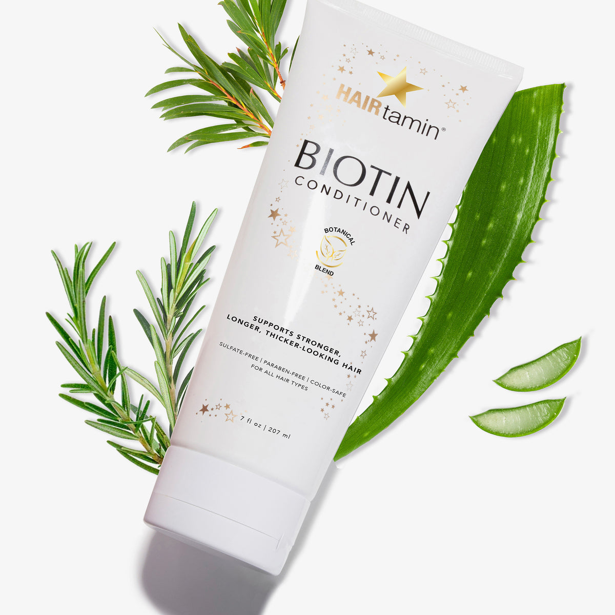 Biotin Conditioner Tube mit Aloe Vera und Rosmarinzweigen auf weißem Hintergrund.