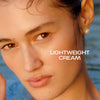 Nahaufnahme einer Frau mit taufrischer Haut und nassem Haar neben dem Text "Lightweight Cream".