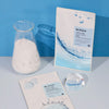 Zwei Päckchen MIZON Joyful Time Essence Mask, eine Flasche mit weißem Pulver und eine Glaskugel sind auf einem hellblauen Hintergrund angeordnet.