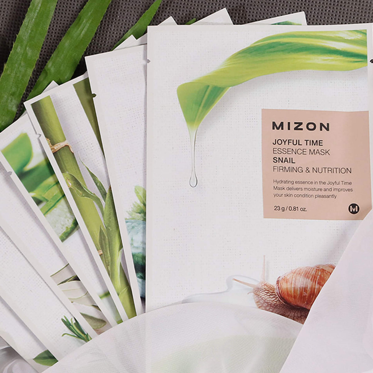Fächerförmig angeordnete Mizon Joyful Time Essence Masken, vorn mit Schnecke und Tropfenmotiv, teils mit Pflanzenillustrationen.