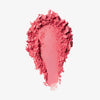 Blush-Puder in der Farbe lucky rose, als kräftiger Farbstrich mit krümeligen, unregelmäßigen Rändern auf weißem Hintergrund.