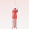 Nahaufnahme des Applikators vom Lip Candy oil über den Rosa Lipgloss fließt.