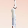 Ein transparenter Tropfen Lip Candy Oil Salted Caramel gleitet vor einem hellbeigenr Hintergrund über den Applikator.