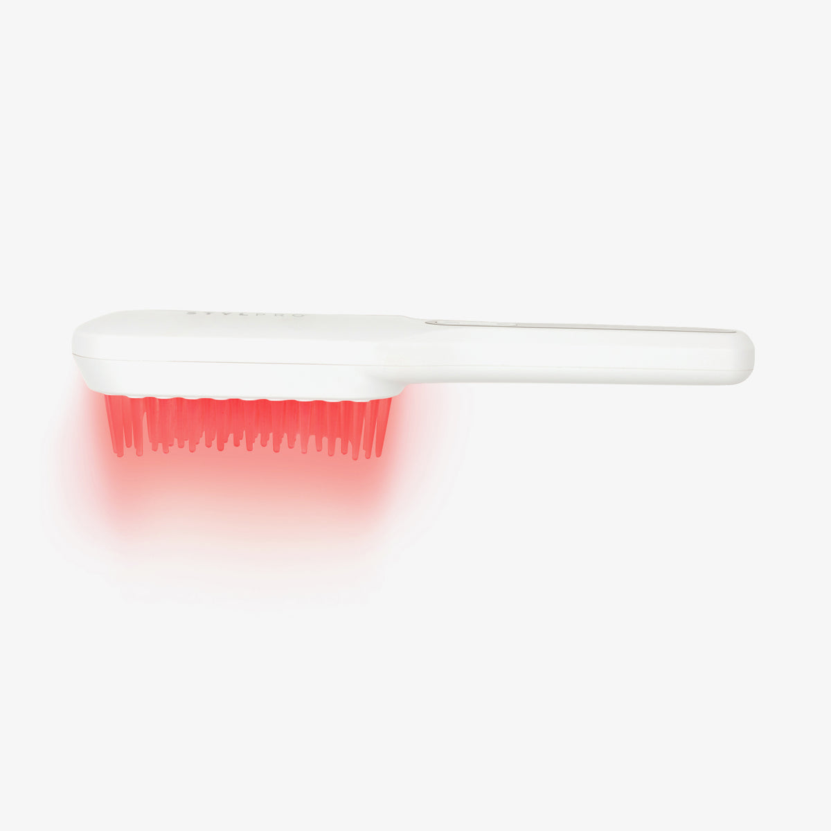 Die STYLPRO Re-Growth Red Light Hair Brush strahlt ein rotes Licht aus ihren Borsten vor einem weißen Hintergrund aus.