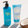 Die Everyday Gradual Tanning Milk (375 ml) und der Body Moisturizer von Bondi Sands stehen auf einer weißen Fläche neben einer halbierten Kokosnuss