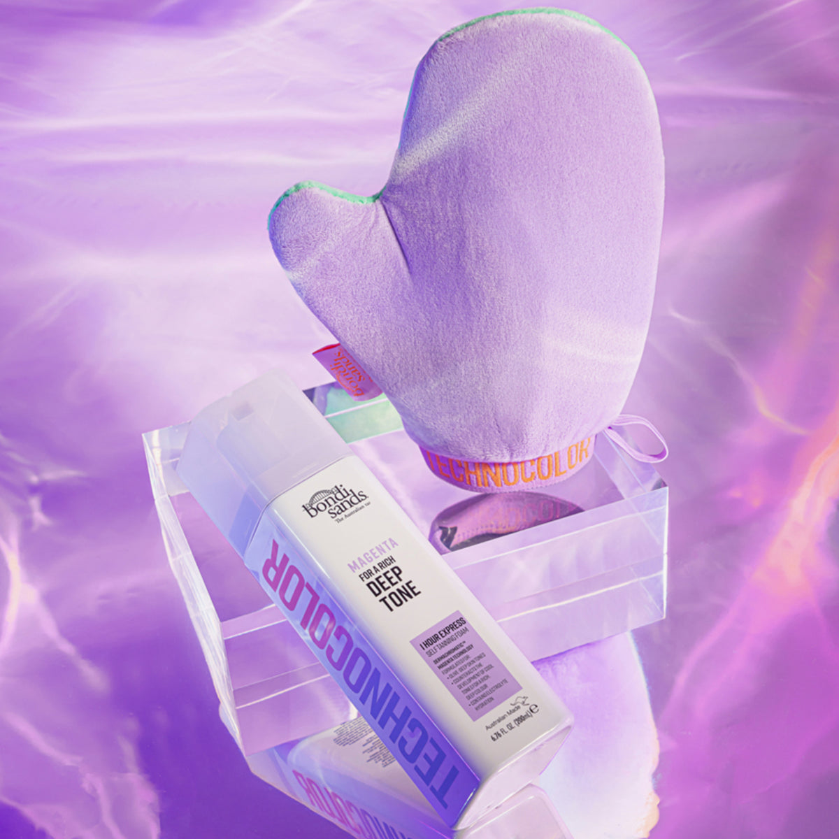 Technocolor 1 Hour Express Self Tanning Foam Magenta neben violettem Bräunungshandschuh auf einem lila schimmernden Hintergrund.