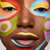 Eine Nahaufnahme des Gesichts einer Frau mit dunklem Hautton mit farbenfroher abstrakter Gesichtsbemalung, erstellt mit  den Colorfix Pastels.