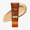 Eine Tube Yummy Skin Serum Tint 3 vor einem warm-beigem Farbmuster.