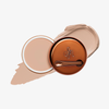 Runde geöffnete bronzefarbene Dose des Yummy Skin Blurring Balm Powder vor einem Farbstreifen der Shade 1.5.