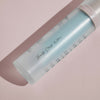 Mattierte Flasche „Cooling Blur Mattifying Primer“ mit dem Text „Beauty Starts Within …“, auf einer blassrosa Oberfläche liegend.