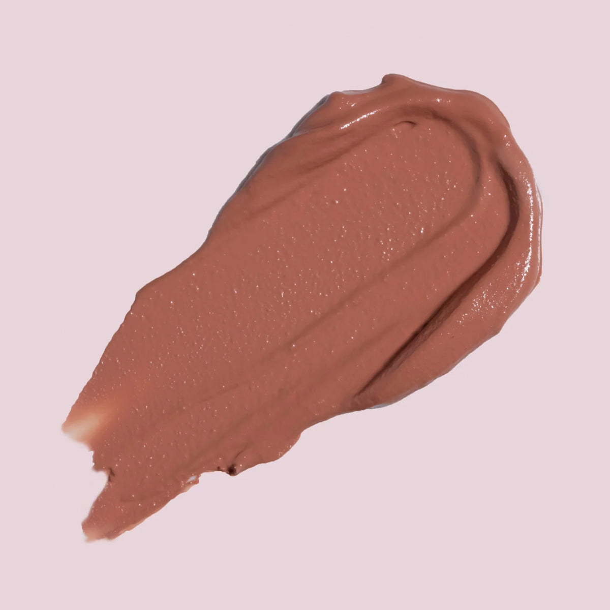 Ein Strich Cream Matte Liquid Lipstick in cremigem Nude-Braun auf blassrosa Hintergrund.