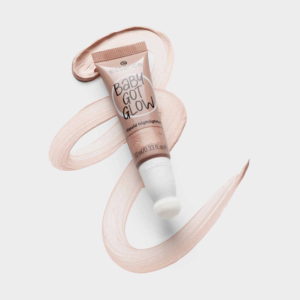 Tube BABY GOT GLOW liquid highlighter 10 liegt auf einem verwischten Farbstreifen auf grauer Oberfläche.