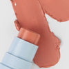 Nahaufnahme des Blush Stick – 2-in-1 Creme Rouge mit Pinsel in der Farbe Blossom neben cremigem Farbmuster.