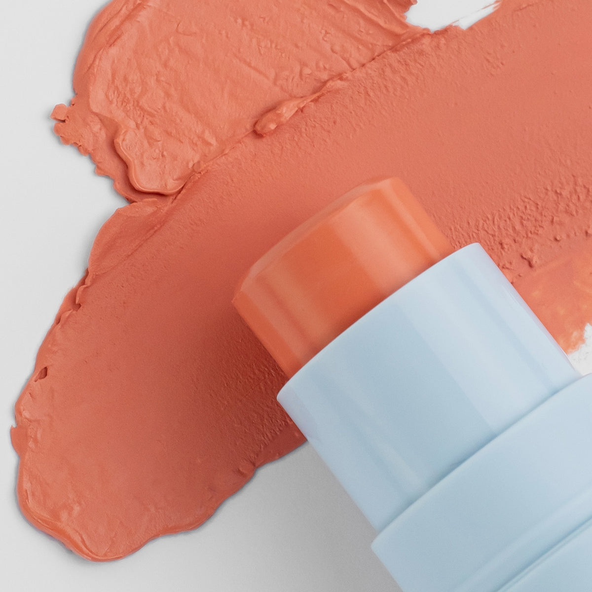 Nahaufnahme des Blush Stick - 2-in-1
Creme Rouge mit Pinsel in der Farbe Coral neben cremigem Farbmuster.