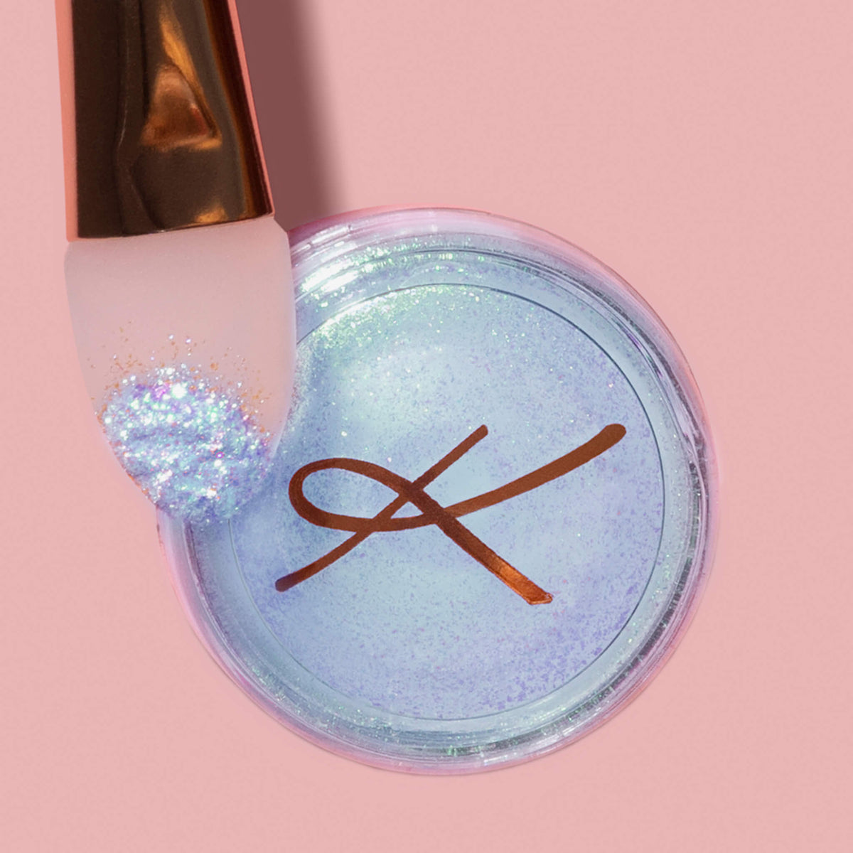 Der K1: Eye & Lip Glitter Pigment Brush liegt auf einem Tiegel Karla Cosmetics Glitter Pot auf rosa Hintergrund.