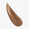 Nahaufnahme der cremigen braune Textur des Lumene INVISIBLE ILLUMINATION Glow Beauty Serum Universal Deep.