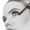Eine Nahaufnahme zeigt, wie eine Frau die Femuline™ Mascara von Mesauda Beauty mit einer gebogenen Bürste auf ihre oberen Wimpern aufträgt.