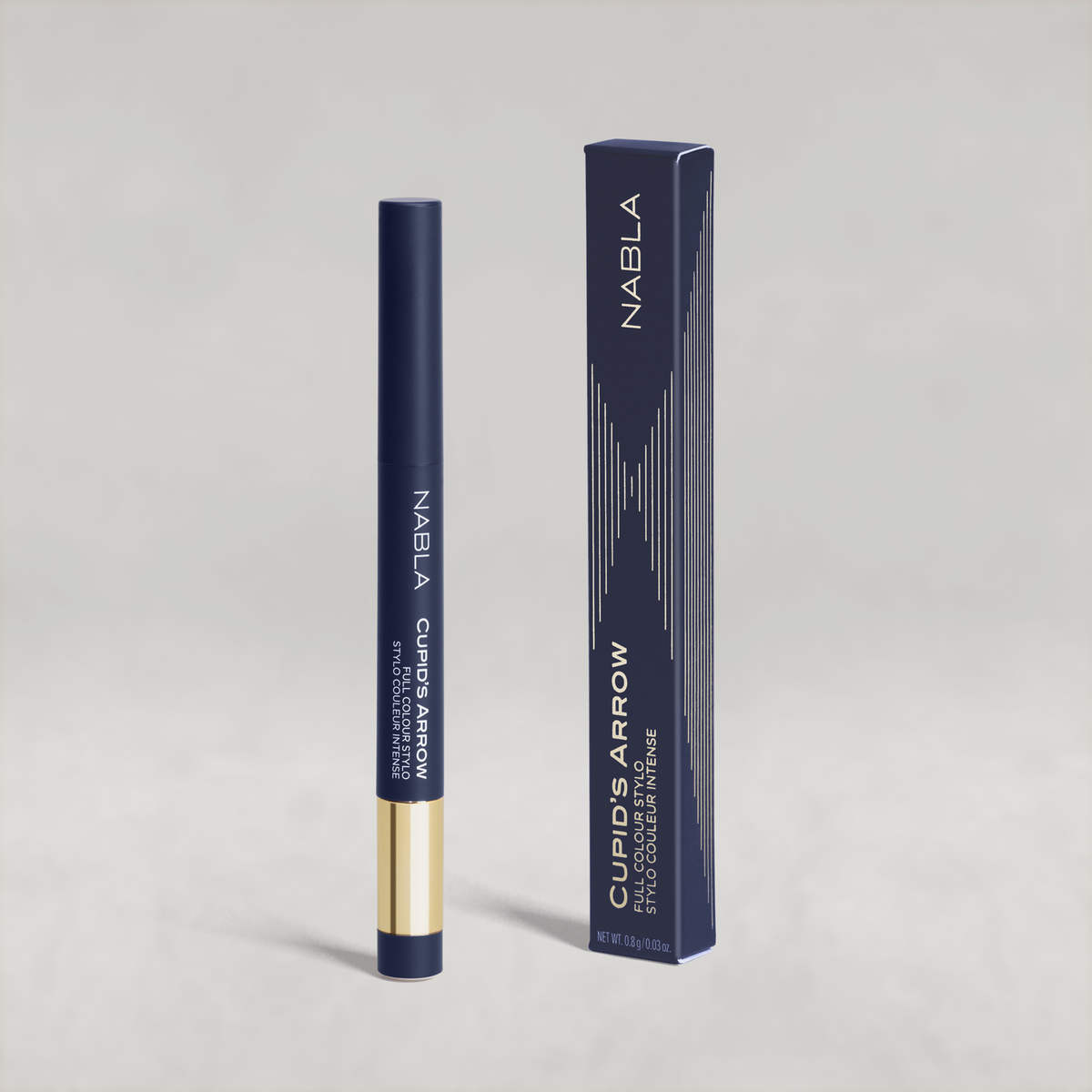 Blauer Lidschatten-Stift mit goldener Kappe von NABLA neben der passenden blauen Umverpackung mit goldenen Designelementen auf hellem Hintergrund.
